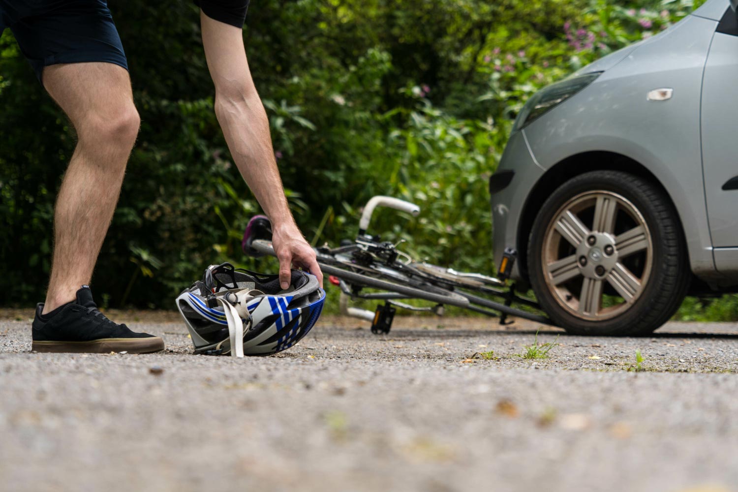 2022_05_Cyclist_picks_up_helmet_after_bike_accident-scaled