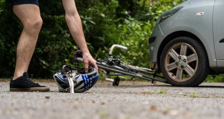 2022_05_Cyclist_picks_up_helmet_after_bike_accident-scaled