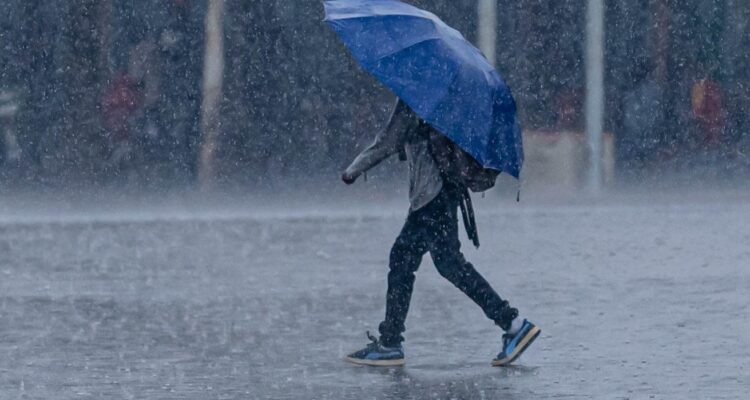 A_man_walks_through_heavy_rain_under_an_umbrella_in_Kigali_Rwanda._Emmanuel_Kwizera